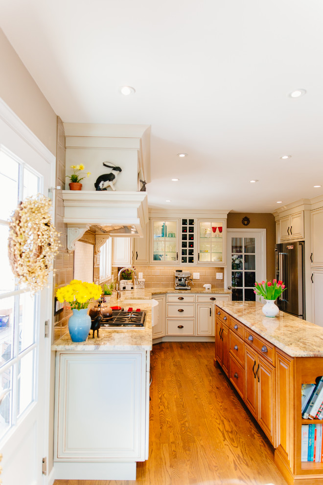Foto på ett litet lantligt beige kök, med en rustik diskho, luckor med upphöjd panel, vita skåp, granitbänkskiva, beige stänkskydd, stänkskydd i glaskakel, rostfria vitvaror, mellanmörkt trägolv, en köksö och brunt golv
