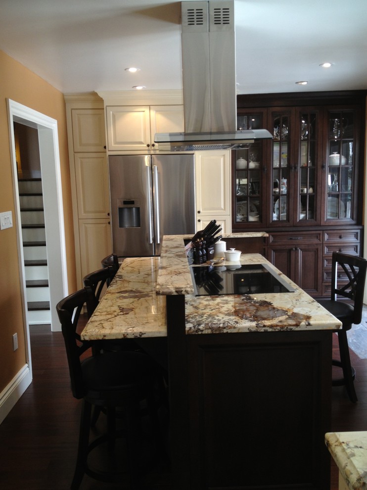 Example of a large classic l-shaped dark wood floor eat-in kitchen design in Toronto with an undermount sink, raised-panel cabinets, beige cabinets, granite countertops, multicolored backsplash, matchstick tile backsplash, stainless steel appliances and an island