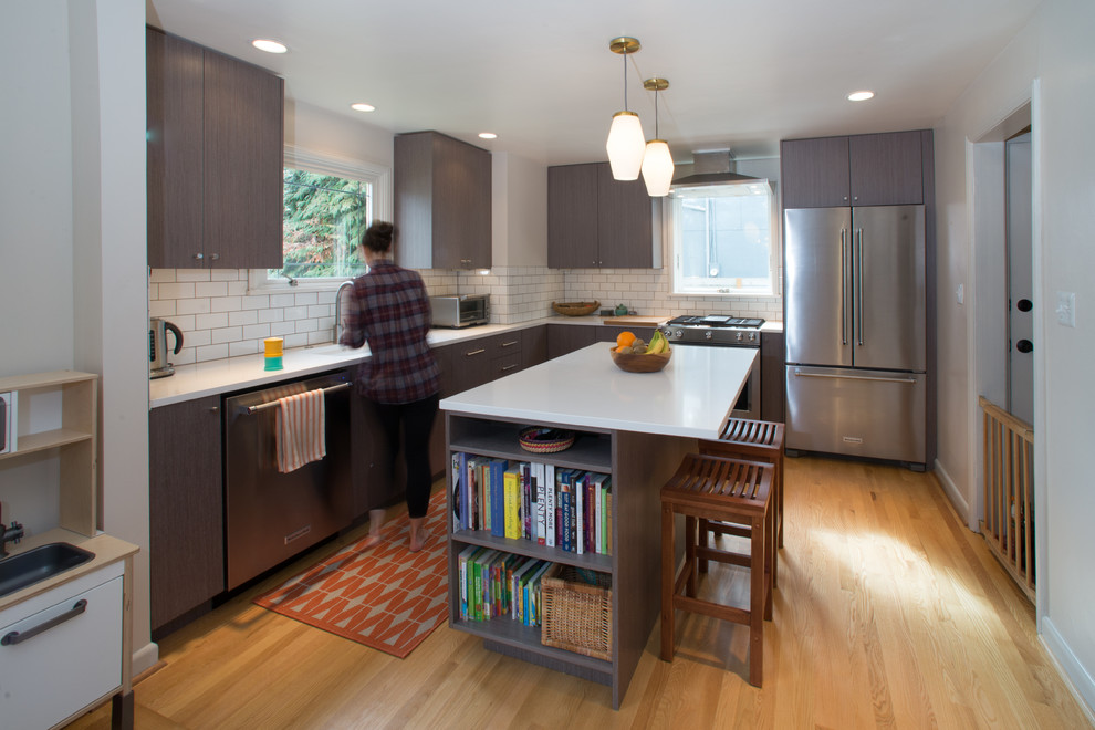 Modern inredning av ett litet kök, med en undermonterad diskho, bänkskiva i kvarts, vitt stänkskydd, stänkskydd i tunnelbanekakel, rostfria vitvaror, ljust trägolv och en köksö