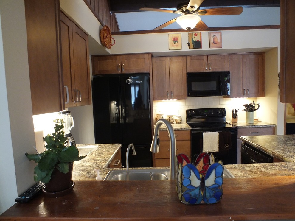 Klassisk inredning av ett mellanstort u-kök, med en nedsänkt diskho, skåp i shakerstil, skåp i mellenmörkt trä, laminatbänkskiva, beige stänkskydd, stänkskydd i keramik, svarta vitvaror och linoleumgolv