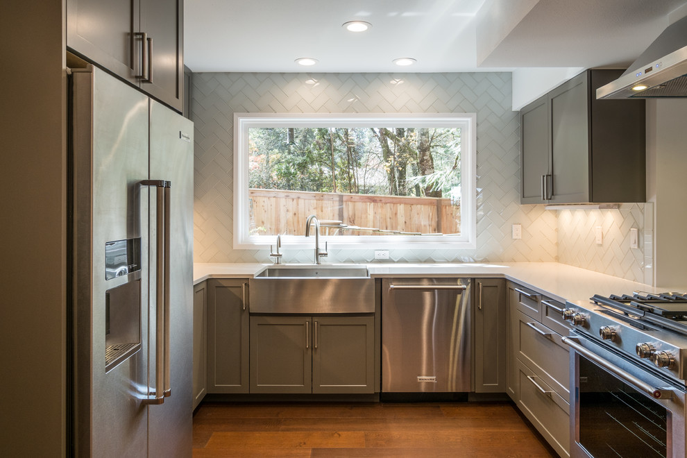 Example of a mid-sized trendy u-shaped dark wood floor kitchen design in Portland with an undermount sink, recessed-panel cabinets, gray cabinets, quartz countertops, white backsplash, glass tile backsplash, stainless steel appliances and a peninsula