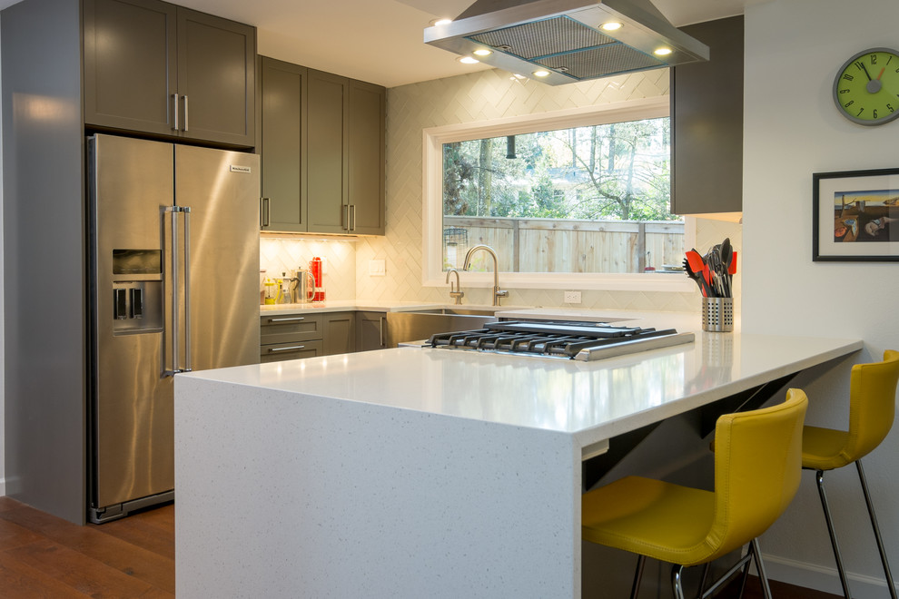 Example of a mid-sized trendy u-shaped dark wood floor kitchen design in Portland with an undermount sink, recessed-panel cabinets, gray cabinets, quartz countertops, white backsplash, glass tile backsplash, stainless steel appliances and a peninsula
