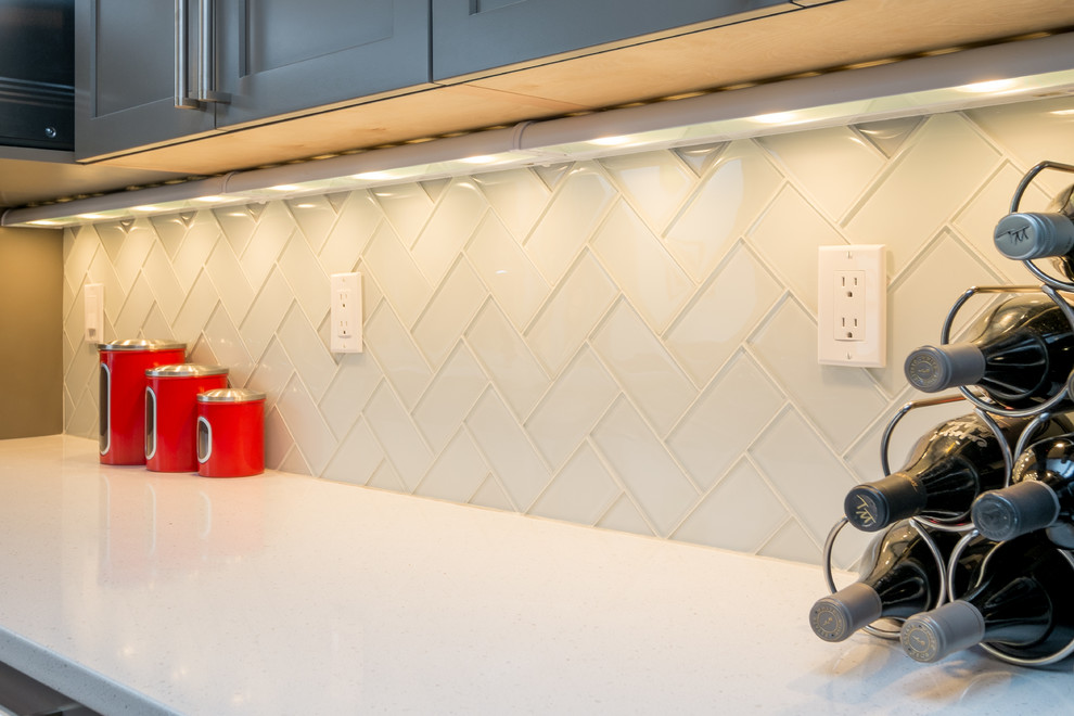Inspiration for a mid-sized transitional u-shaped dark wood floor kitchen remodel in Portland with an undermount sink, recessed-panel cabinets, gray cabinets, quartz countertops, white backsplash, glass tile backsplash, stainless steel appliances and a peninsula