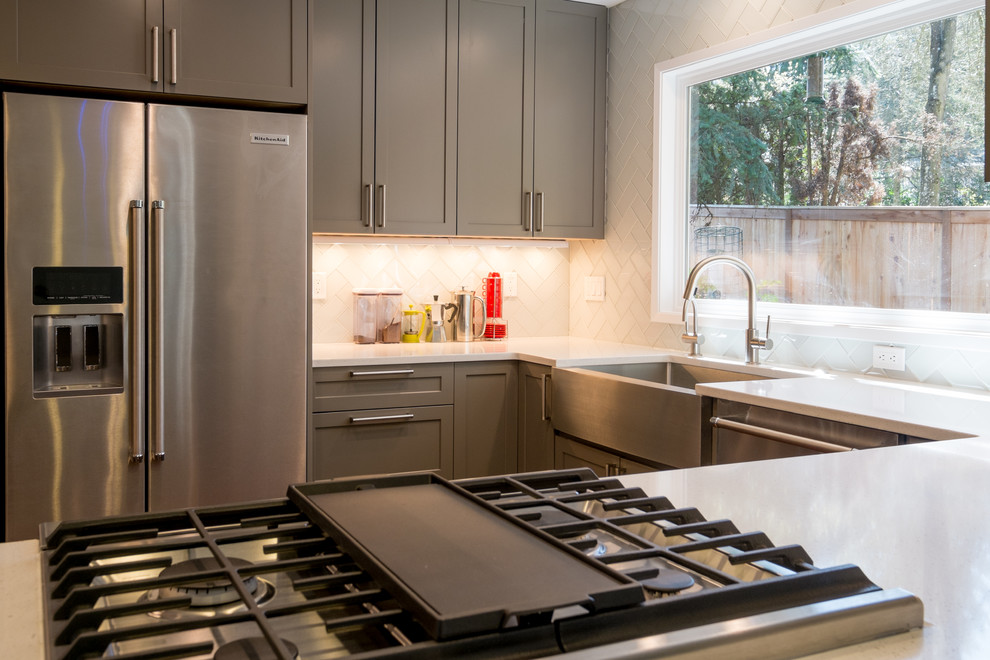 Kitchen - mid-sized transitional u-shaped dark wood floor kitchen idea in Portland with an undermount sink, recessed-panel cabinets, gray cabinets, quartz countertops, white backsplash, glass tile backsplash, stainless steel appliances and a peninsula