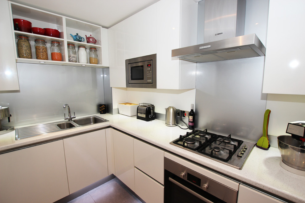 Moderne Küche ohne Insel in L-Form mit weißen Schränken und Küchenrückwand in Metallic in London