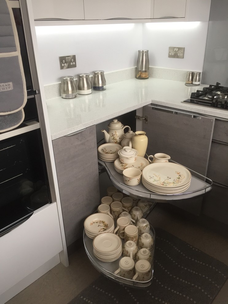 Exempel på ett avskilt, litet modernt vit vitt u-kök, med en undermonterad diskho, släta luckor, grå skåp, bänkskiva i kvartsit, grått stänkskydd, glaspanel som stänkskydd, integrerade vitvaror och vinylgolv