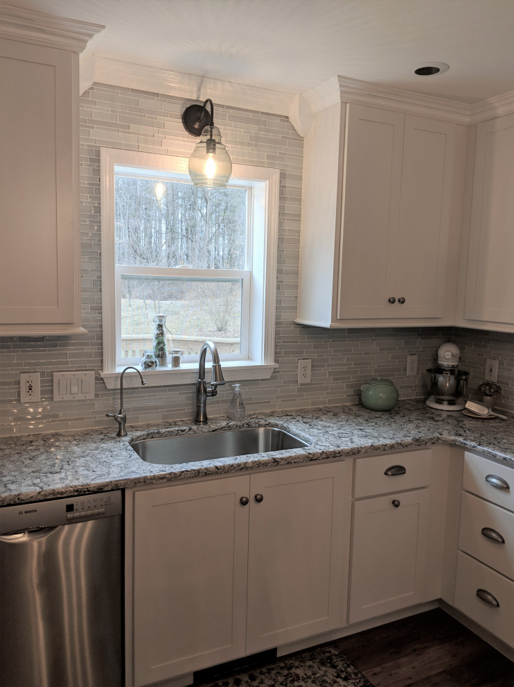 Klassisk inredning av ett litet vit vitt kök, med en undermonterad diskho, skåp i shakerstil, vita skåp, bänkskiva i kvarts, blått stänkskydd, stänkskydd i glaskakel, rostfria vitvaror, mellanmörkt trägolv och flerfärgat golv