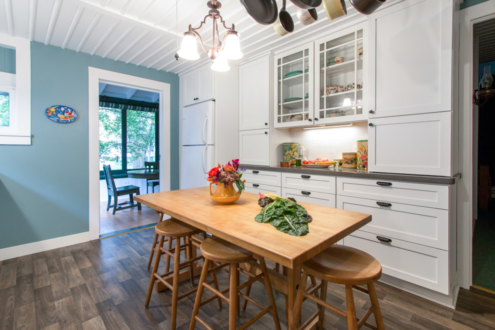 Inspiration for a small farmhouse galley medium tone wood floor enclosed kitchen remodel in Milwaukee with a farmhouse sink, flat-panel cabinets, white cabinets, quartz countertops, white backsplash, ceramic backsplash, stainless steel appliances and no island
