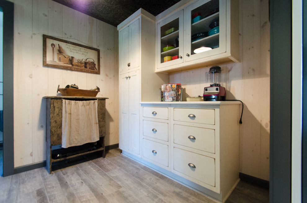 Small cottage u-shaped medium tone wood floor and multicolored floor kitchen pantry photo in New York with a farmhouse sink, shaker cabinets, white cabinets, quartz countertops, glass tile backsplash, stainless steel appliances and an island