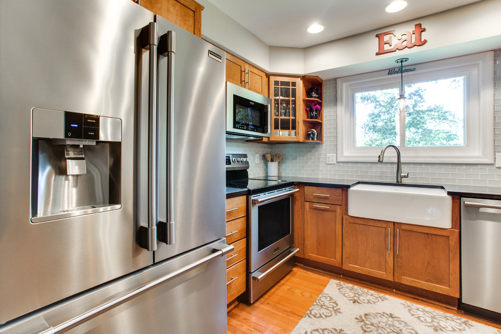 Small transitional u-shaped medium tone wood floor kitchen photo in DC Metro with a farmhouse sink, shaker cabinets, granite countertops, gray backsplash, subway tile backsplash, stainless steel appliances and a peninsula