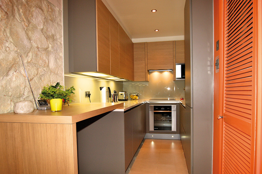 Imagen de cocina estrecha minimalista pequeña con armarios con paneles lisos, puertas de armario grises y península