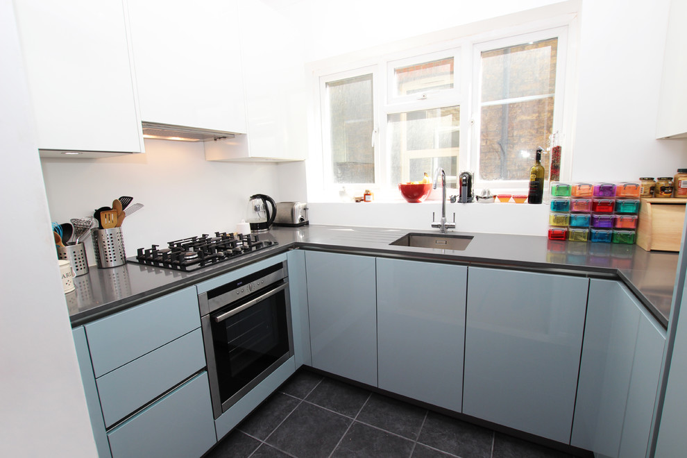 Esempio di una cucina ad U minimalista chiusa con ante di vetro, ante blu, top in quarzite, elettrodomestici in acciaio inossidabile e nessuna isola