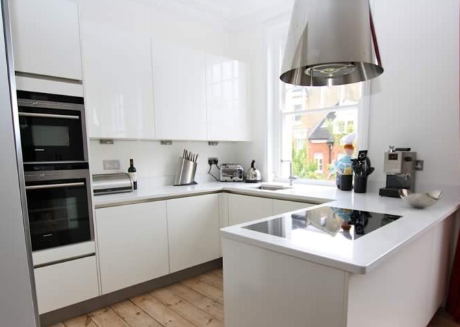 Minimalist u-shaped kitchen photo in London with white cabinets