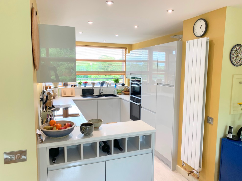 Foto di una piccola cucina minimal con ante lisce, ante grigie, top in quarzite, paraspruzzi bianco, elettrodomestici neri, pavimento in vinile, pavimento grigio e top bianco