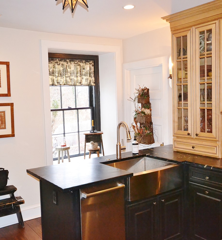 Modern inredning av ett litet kök, med en rustik diskho, luckor med upphöjd panel, beige skåp, bänkskiva i täljsten, vitt stänkskydd, rostfria vitvaror och mellanmörkt trägolv