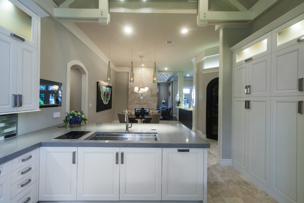 Inspiration for a large transitional u-shaped porcelain tile and beige floor kitchen remodel with raised-panel cabinets, white cabinets, gray backsplash, glass tile backsplash, stainless steel appliances, an island, an undermount sink and solid surface countertops