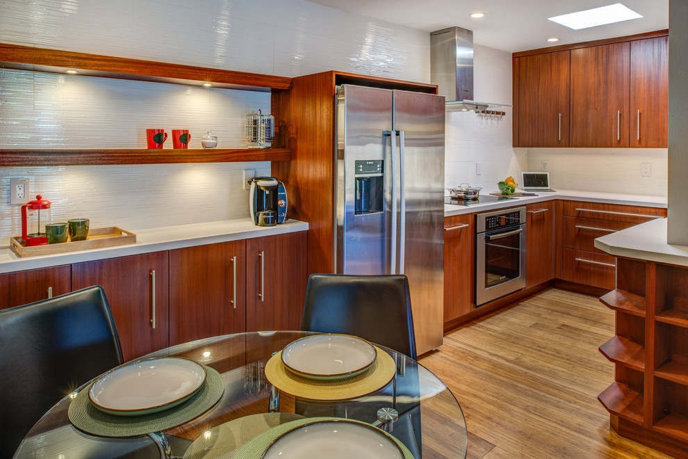 This is an example of a small contemporary u-shaped kitchen/diner in San Francisco with a belfast sink, flat-panel cabinets, dark wood cabinets, composite countertops, white splashback, porcelain splashback, stainless steel appliances, bamboo flooring and no island.
