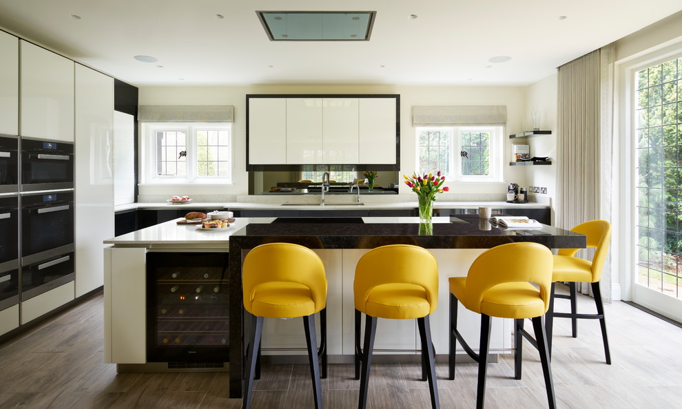 Esempio di una cucina design con ante lisce, ante bianche, elettrodomestici neri, pavimento in legno massello medio e pavimento marrone