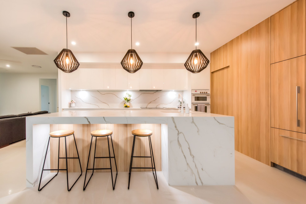 Trendy l-shaped beige floor kitchen photo in Sydney with quartz countertops, flat-panel cabinets, medium tone wood cabinets, white backsplash, stone slab backsplash, white appliances, an island and white countertops