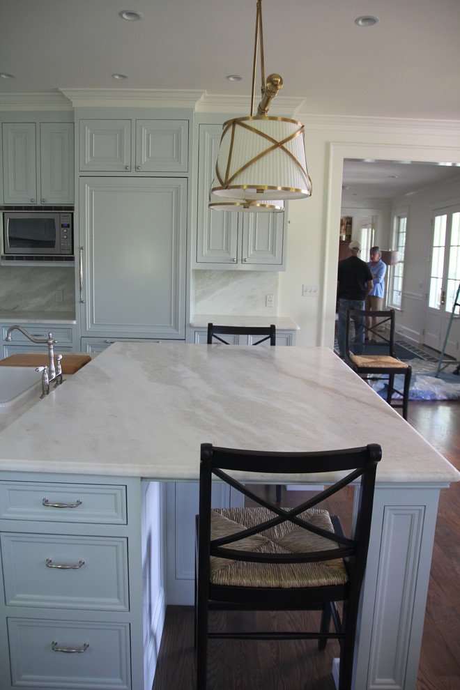 Exempel på ett stort klassiskt kök, med en rustik diskho, släta luckor, vita skåp, marmorbänkskiva, vitt stänkskydd, stänkskydd i sten, integrerade vitvaror, mellanmörkt trägolv och en köksö