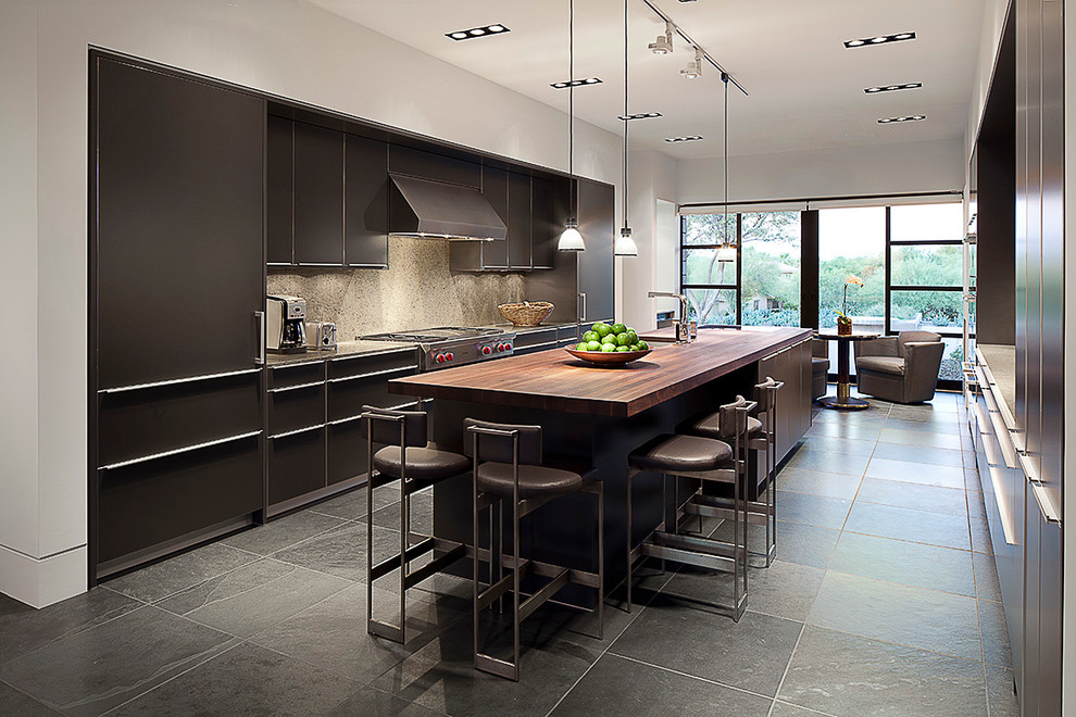 Example of a huge minimalist galley slate floor kitchen design in Phoenix with an integrated sink, flat-panel cabinets, gray cabinets, wood countertops, beige backsplash, stone slab backsplash and stainless steel appliances