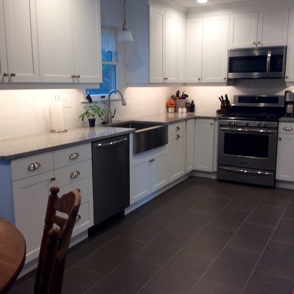 Foto på ett mellanstort funkis kök, med en rustik diskho, skåp i shakerstil, vita skåp, granitbänkskiva, vitt stänkskydd, stänkskydd i tunnelbanekakel, rostfria vitvaror, betonggolv och grått golv