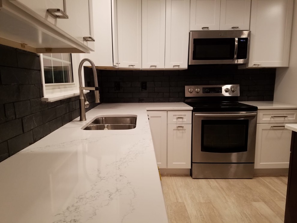 Modern inredning av ett mellanstort vit vitt kök, med en dubbel diskho, skåp i shakerstil, vita skåp, bänkskiva i kvarts, grått stänkskydd, stänkskydd i stenkakel, rostfria vitvaror, laminatgolv, en köksö och beiget golv