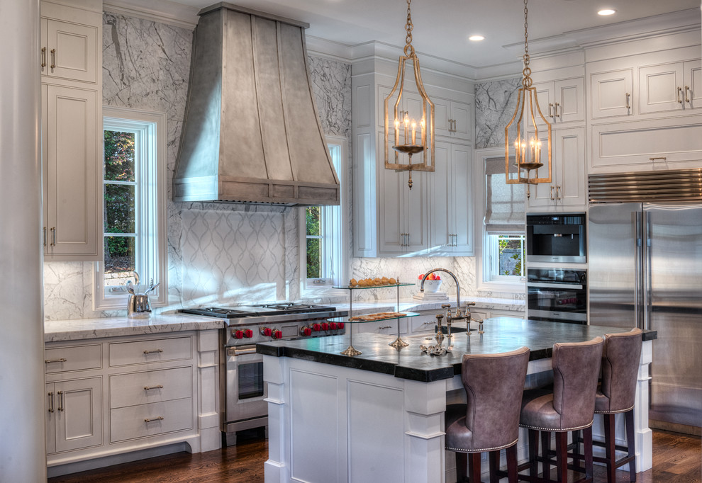 Open concept kitchen - mid-sized transitional l-shaped dark wood floor open concept kitchen idea in Other with a farmhouse sink, beaded inset cabinets, white cabinets, marble countertops, white backsplash, stone slab backsplash, stainless steel appliances and an island