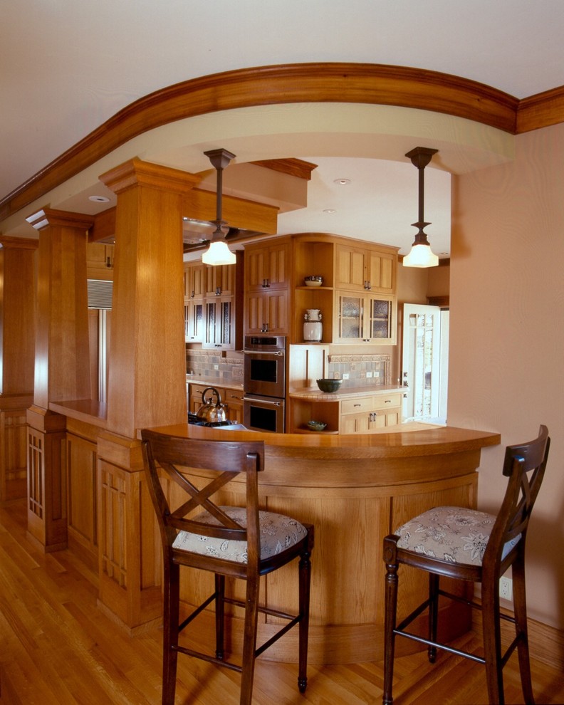 Cette image montre une cuisine ouverte craftsman en L et bois brun avec un placard avec porte à panneau encastré, plan de travail carrelé, une crédence grise, une crédence en céramique et un électroménager en acier inoxydable.