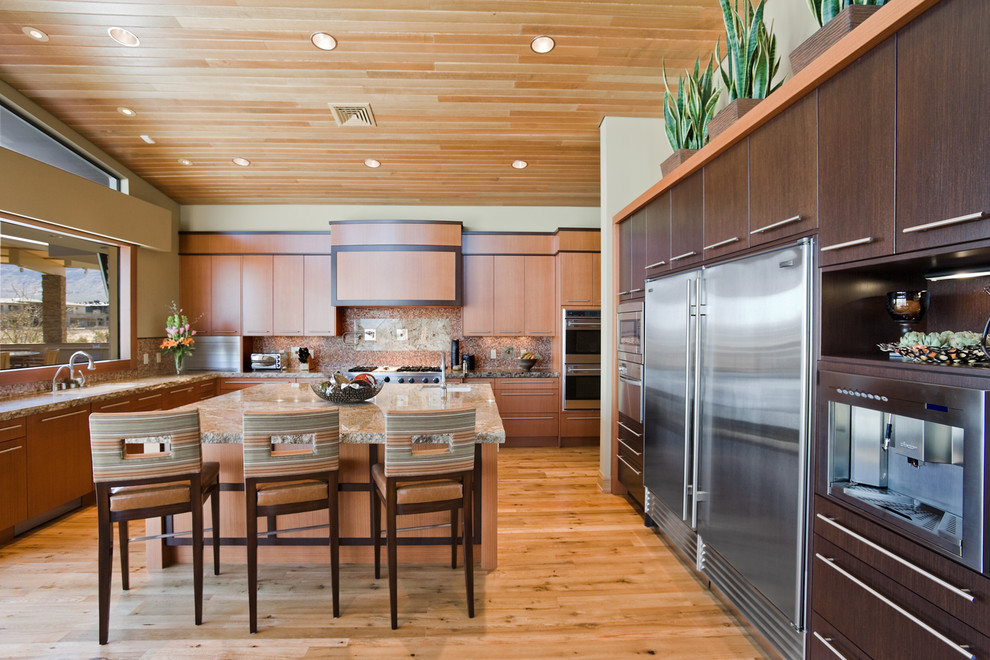Moderne Küche in U-Form mit flächenbündigen Schrankfronten, dunklen Holzschränken, Glasrückwand und Küchengeräten aus Edelstahl in Las Vegas