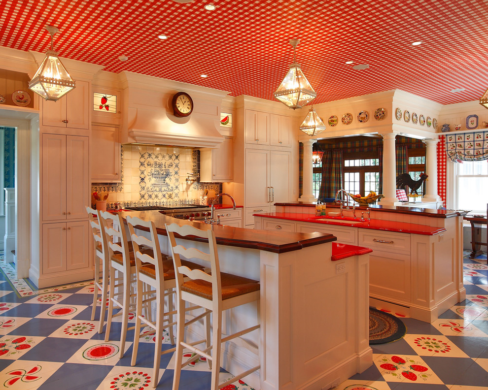 Inredning av ett klassiskt röd rött kök, med en undermonterad diskho, luckor med infälld panel, beige skåp, träbänkskiva, flerfärgad stänkskydd, integrerade vitvaror och flerfärgat golv