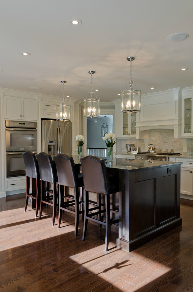 Inspiration for a large transitional l-shaped medium tone wood floor kitchen remodel in Other with shaker cabinets, white cabinets, white backsplash, glass tile backsplash, stainless steel appliances and an island
