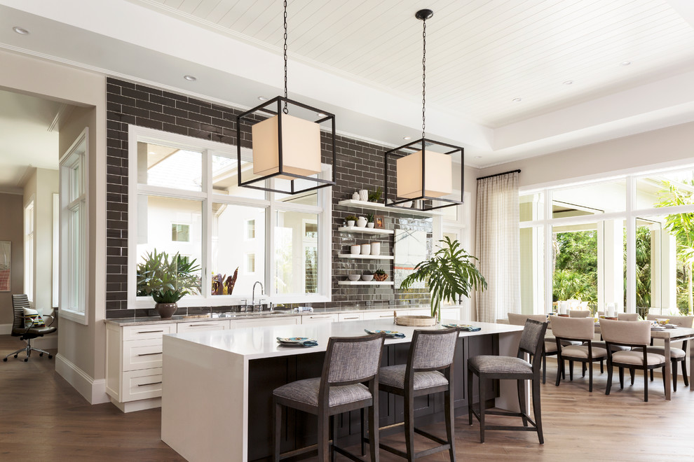 Mid-sized transitional single-wall dark wood floor and brown floor eat-in kitchen photo in Miami with an undermount sink, shaker cabinets, white cabinets, quartzite countertops, brown backsplash, subway tile backsplash and an island