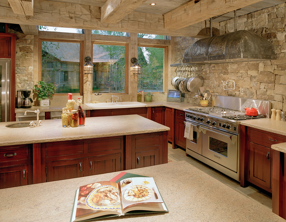 Example of a mountain style l-shaped kitchen design in Other with a drop-in sink, distressed cabinets and stainless steel appliances