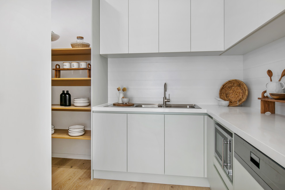 Inredning av ett modernt vit vitt kök, med en dubbel diskho, grå skåp, vitt stänkskydd och rostfria vitvaror