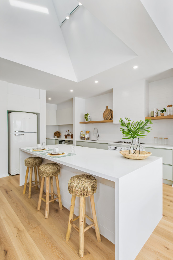 Einzeilige Maritime Wohnküche mit Unterbauwaschbecken, Küchenrückwand in Weiß, Küchengeräten aus Edelstahl, Kücheninsel, weißer Arbeitsplatte und gewölbter Decke in Melbourne