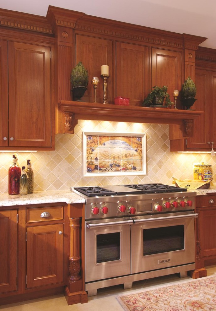 Immagine di una cucina tradizionale con ante con riquadro incassato, ante in legno bruno, paraspruzzi beige, elettrodomestici in acciaio inossidabile e paraspruzzi in pietra calcarea