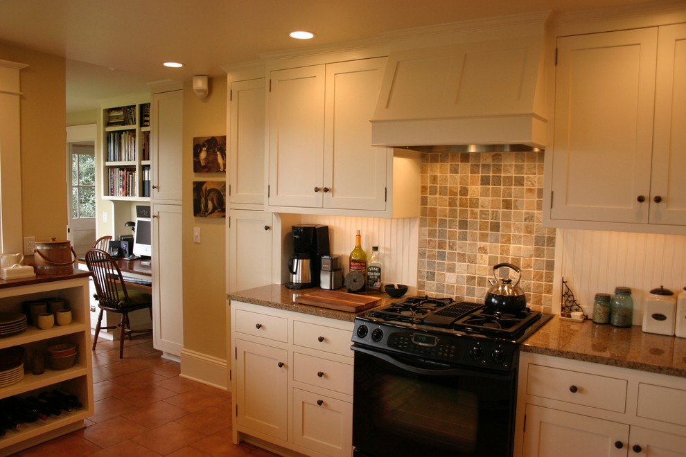 Example of a large cottage u-shaped ceramic tile enclosed kitchen design in Seattle with a farmhouse sink, shaker cabinets, white cabinets, granite countertops, multicolored backsplash, ceramic backsplash, black appliances and no island