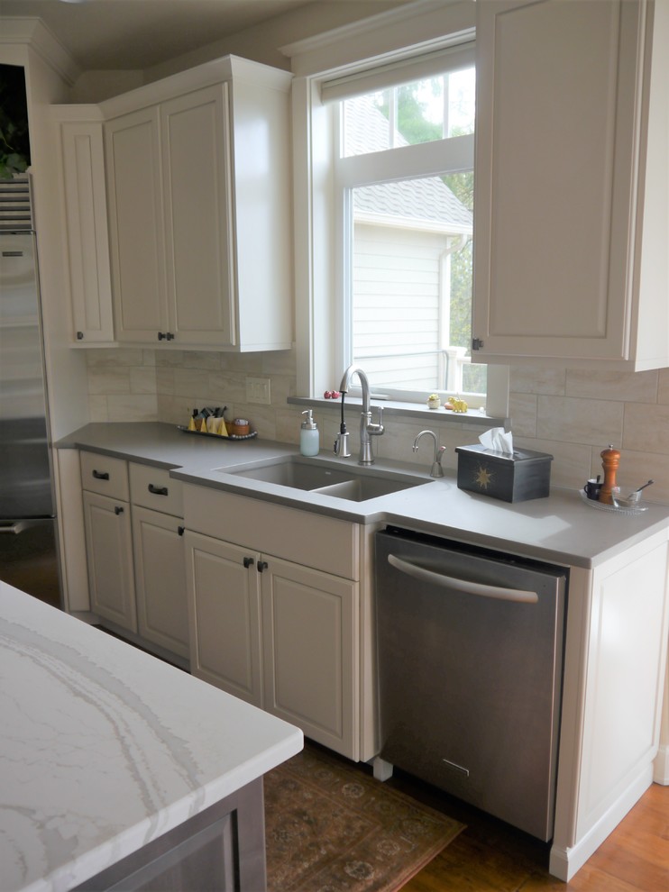 Photo of a large country u-shaped kitchen/diner in Seattle with a submerged sink, raised-panel cabinets, white cabinets, engineered stone countertops, beige splashback, porcelain splashback, stainless steel appliances, medium hardwood flooring, an island, brown floors and multicoloured worktops.