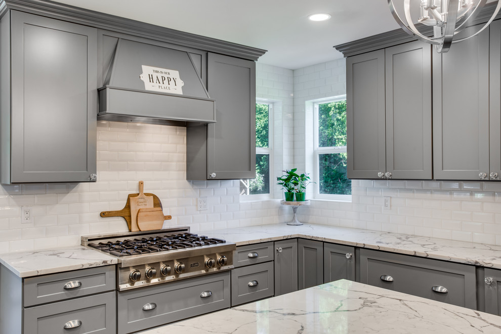 Inspiration for a large traditional l-shaped kitchen/diner in Portland with a belfast sink, shaker cabinets, grey cabinets, engineered stone countertops, white splashback, ceramic splashback, stainless steel appliances, plywood flooring, an island, brown floors and white worktops.