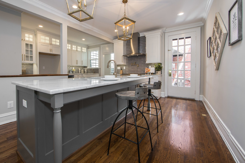 Mid-sized trendy l-shaped dark wood floor and brown floor enclosed kitchen photo in Richmond with an undermount sink, shaker cabinets, white cabinets, marble countertops, gray backsplash, porcelain backsplash, stainless steel appliances and an island