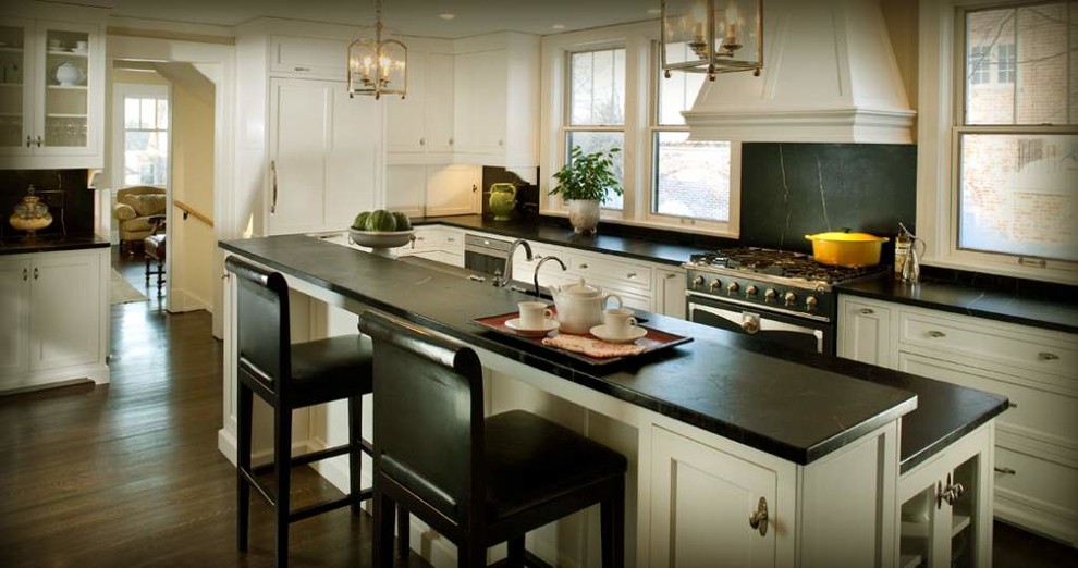 This is an example of a large traditional u-shaped enclosed kitchen in Baltimore with a submerged sink, recessed-panel cabinets, white cabinets, soapstone worktops, black splashback, stone slab splashback, stainless steel appliances, dark hardwood flooring, an island and brown floors.