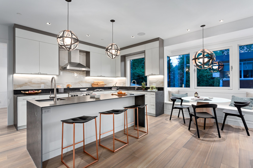 Inspiration for a contemporary u-shaped kitchen/diner in Vancouver with an island, a submerged sink, flat-panel cabinets, white cabinets, multi-coloured splashback, stainless steel appliances, medium hardwood flooring, brown floors and black worktops.