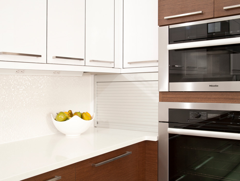 Cette photo montre une cuisine tendance avec un placard à porte plane, une crédence blanche et un électroménager en acier inoxydable.