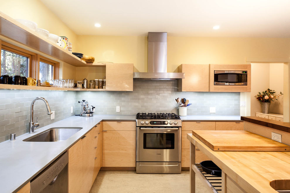 Exempel på ett rustikt l-kök, med rostfria vitvaror, en undermonterad diskho, släta luckor, skåp i ljust trä, grått stänkskydd och en köksö