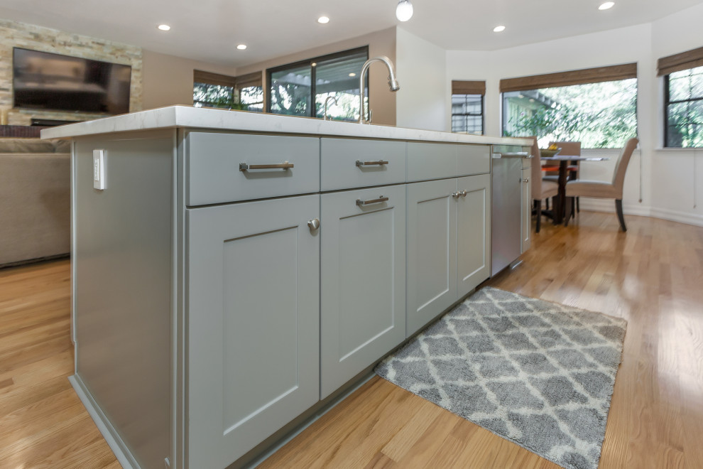 Exempel på ett mellanstort modernt vit vitt kök, med en undermonterad diskho, skåp i shakerstil, vita skåp, bänkskiva i kvarts, beige stänkskydd, stänkskydd i stenkakel, rostfria vitvaror, ljust trägolv, en köksö och gult golv