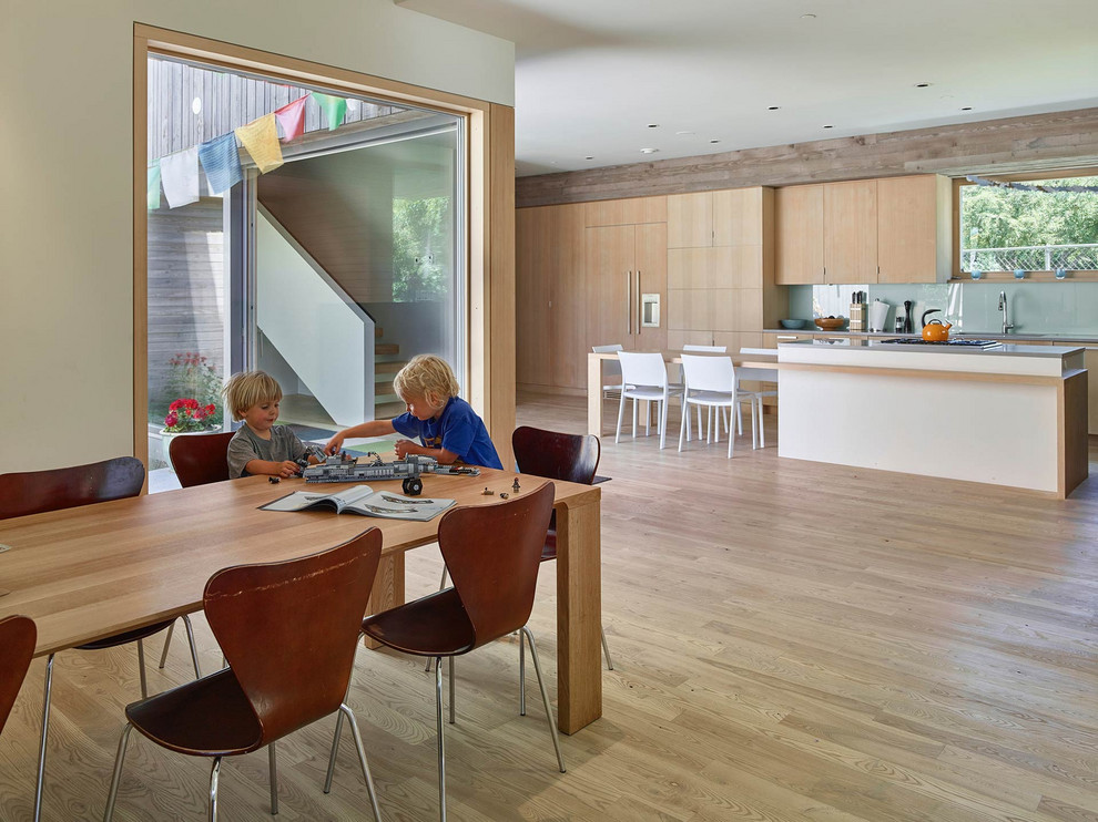 Inspiration för mellanstora moderna linjära grått kök med öppen planlösning, med släta luckor, skåp i ljust trä, bänkskiva i kvarts, en köksö, en undermonterad diskho, glaspanel som stänkskydd, integrerade vitvaror, ljust trägolv och beiget golv