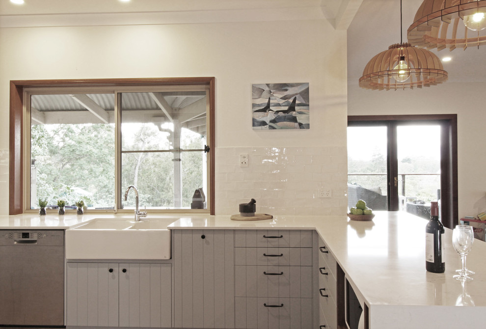 Exempel på ett avskilt, stort lantligt vit vitt u-kök, med en rustik diskho, släta luckor, blå skåp, bänkskiva i kvarts, vitt stänkskydd, stänkskydd i tunnelbanekakel, rostfria vitvaror, mellanmörkt trägolv, en halv köksö och brunt golv