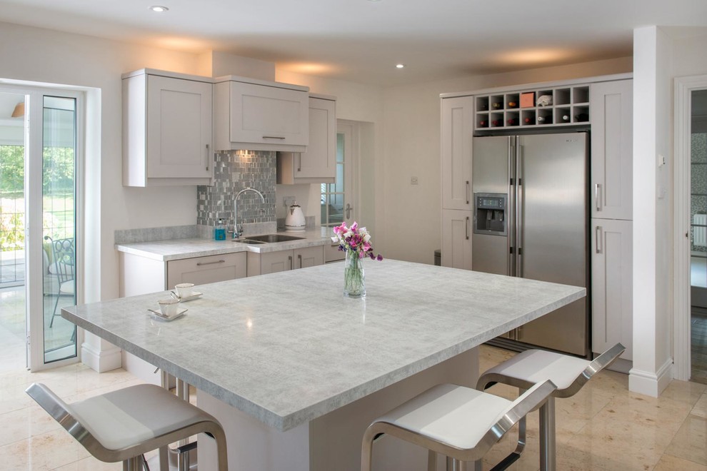 Photo of a large classic l-shaped enclosed kitchen in Ottawa with a submerged sink, shaker cabinets, white cabinets, engineered stone countertops, metallic splashback, metal splashback, stainless steel appliances, limestone flooring, an island and beige floors.