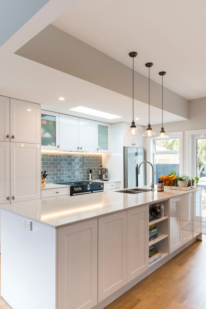 Mid-sized elegant galley gray floor kitchen pantry photo in Christchurch with an undermount sink, shaker cabinets, white cabinets, quartz countertops, gray backsplash, subway tile backsplash, stainless steel appliances and an island